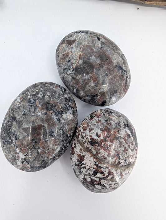 Close-up of polished Yooperlite palm stone showing natural speckled texture