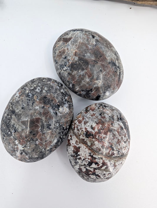 Close-up of polished Yooperlite palm stone showing natural speckled texture