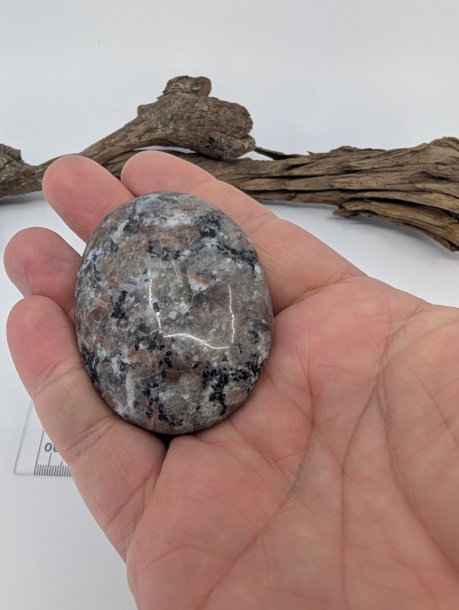 Yooperlite palm stone shown in hand – smooth polished pocket stone