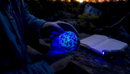 Hands holding glowing fluorescent mineral under UV light