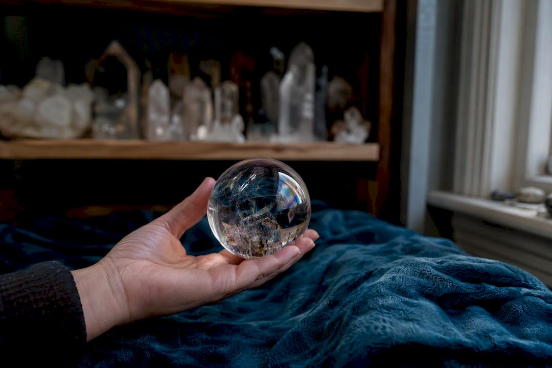 Hand holding polished crystal sphere indoors