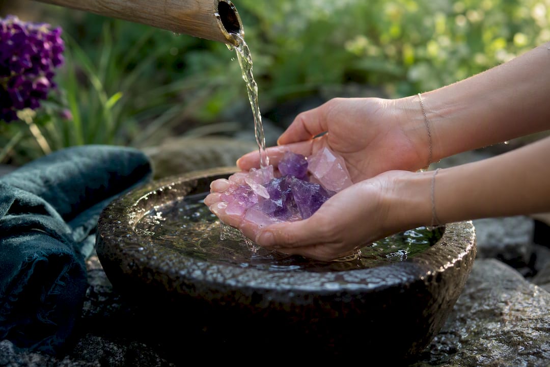 Hands rinsing quartz crystals under water
