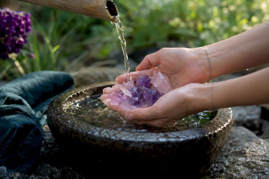 Hands rinsing quartz crystals under water