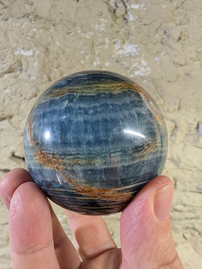 Polished banded calcite sphere with rich blue and sienna tones