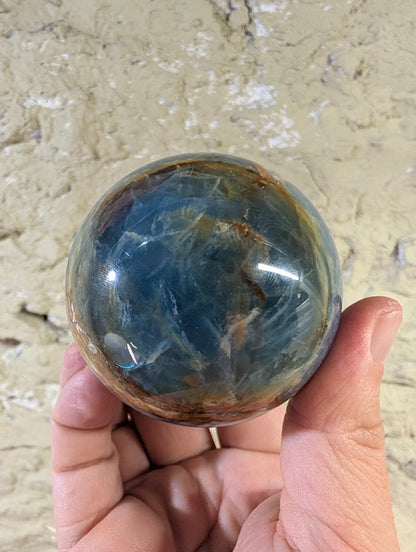 Polished banded calcite sphere with rich blue and sienna tones