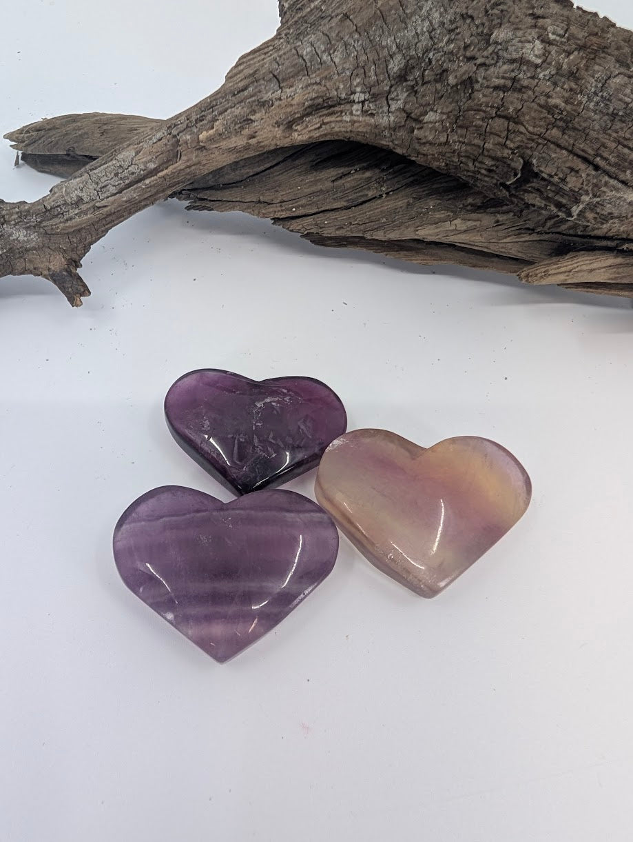 Trio of small purple Fluorite hearts on driftwood.