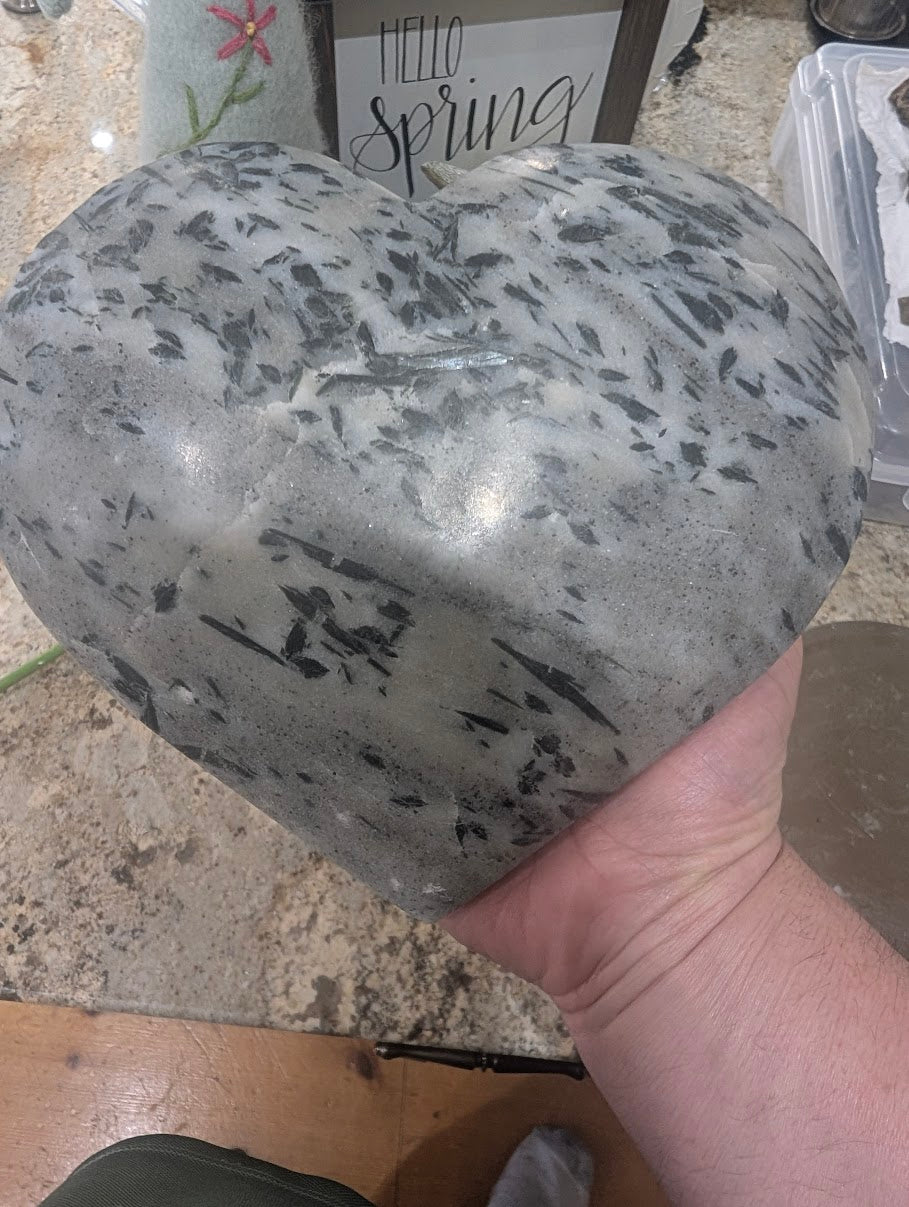 A large 8-inch actinolite in quartz heart held in a hand to demonstrate the significant scale and 3.17kg weight.