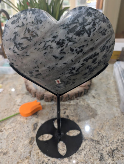 The reverse side of a large polished actinolite in quartz heart showing consistent inclusion density and custom stand.