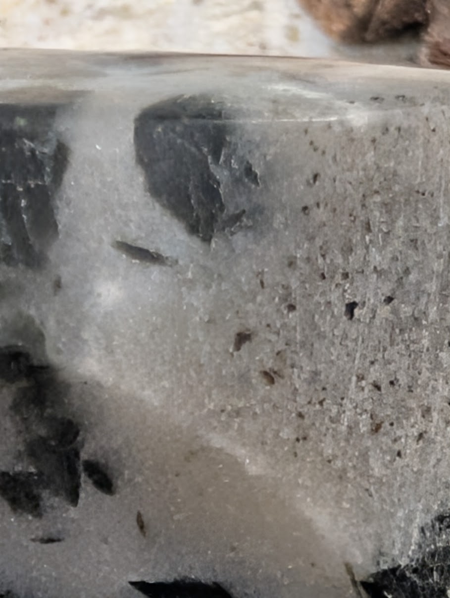 Extreme close-up of the polished edge of a quartz heart revealing granular metamorphic matrix and deep green inclusions.