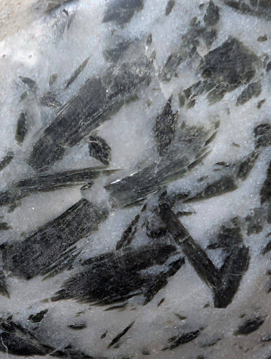 Detailed macro view of forest-green actinolite "hair" suspended within a translucent milky quartz host.
