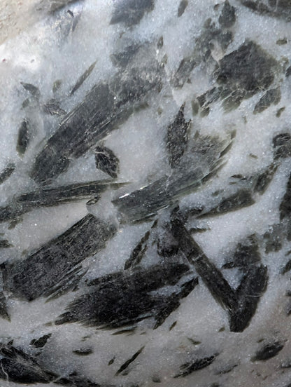 Detailed macro view of forest-green actinolite "hair" suspended within a translucent milky quartz host.
