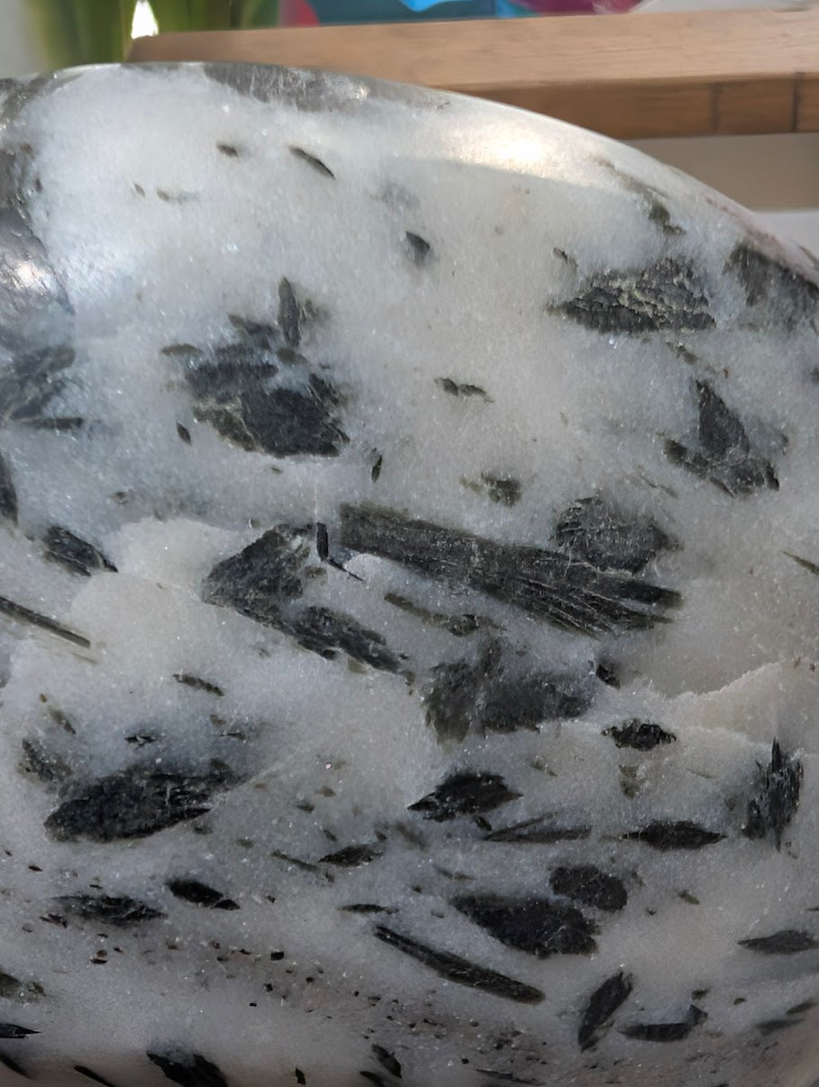 Detailed macro view of forest-green actinolite "hair" suspended within a translucent milky quartz host.