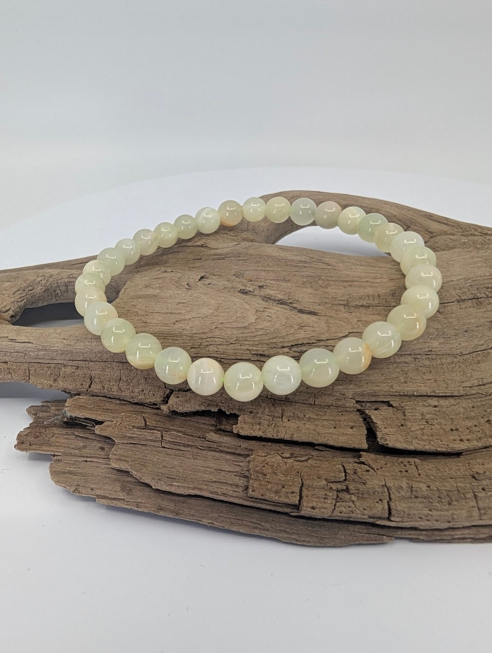 Afghan Jade serpentine bracelet with 6mm beads displayed on driftwood