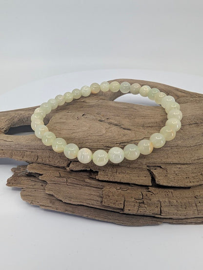 Afghan Jade serpentine bracelet with 6mm beads displayed on driftwood