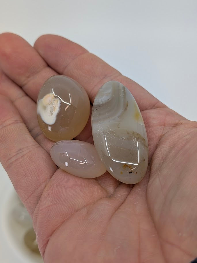 Agate tumbled stones shown in hand for scale