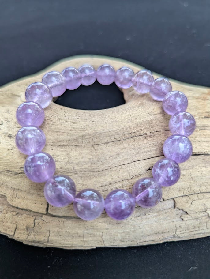 11mm High Quality Brazilian Amethyst beaded stretch bracelet on driftwood, displaying natural purple quartz beads strung on clear elastic.