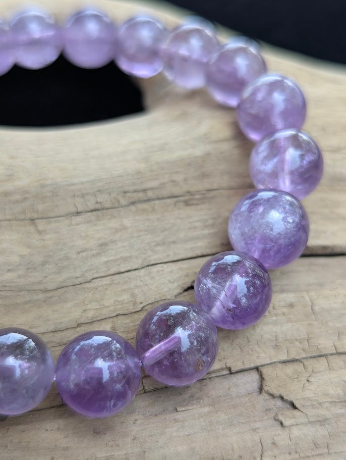Macro photograph of 11mm High Quality Brazilian Amethyst round beads showing high glassy luster and delicate violet colour zoning.