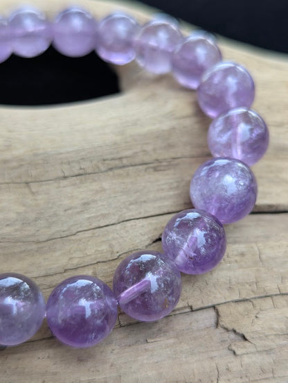 Macro photograph of 11mm High Quality Brazilian Amethyst round beads showing high glassy luster and delicate violet colour zoning.