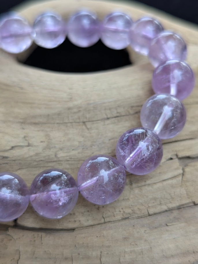 Macro close-up of 12mm High Quality Brazilian Amethyst beads highlighting natural internal veils, high polish, and lilac quartz clarity.