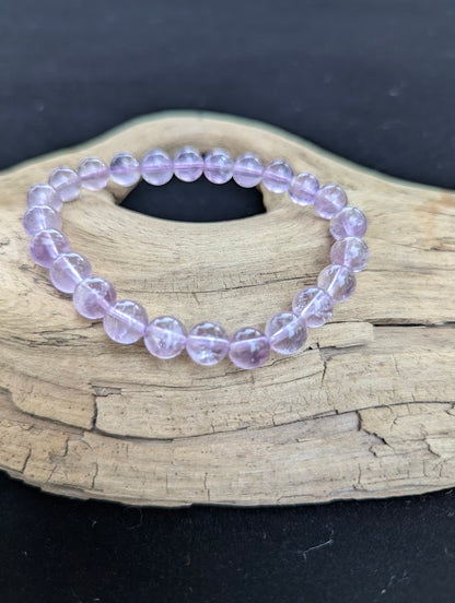 8mm High Quality Brazilian Amethyst beaded stretch bracelet on a driftwood display, showing light purple crystalline quartz.