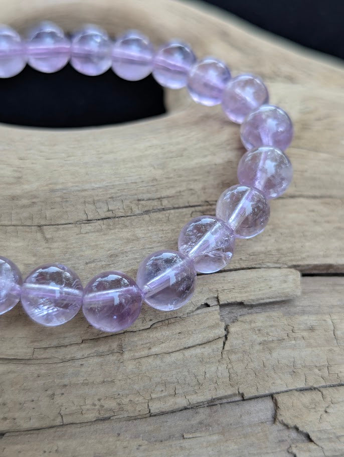 Macro close-up of 8mm High Quality Brazilian Amethyst beads showing refined polish and light transmission through the quartz matrix.