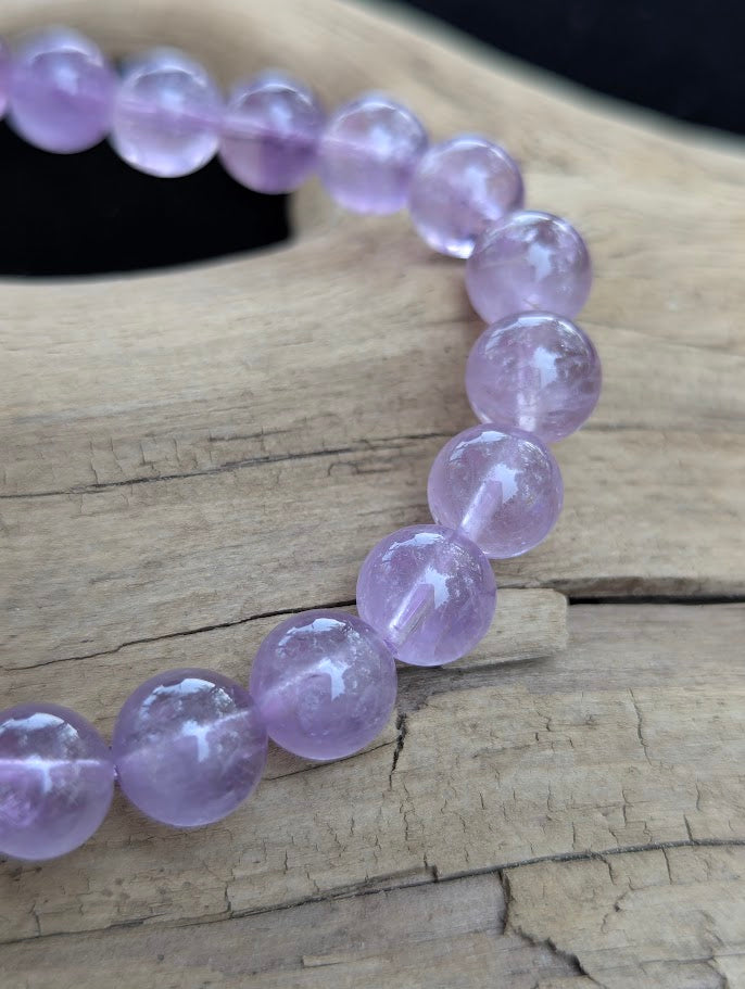 Macro view of 9mm High Quality Brazilian Amethyst beads highlighting smooth spherical lapidary polish and natural inclusions.