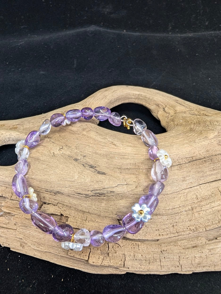 Full view of a children's Amethyst bracelet with polished freeform nuggets and iridescent flower charms on a driftwood background.