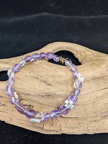 Full view of a children's Amethyst bracelet with polished freeform nuggets and iridescent flower charms on a driftwood background.