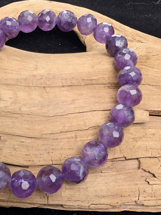 Macro close-up of 8mm faceted Amethyst beads highlighting the geometric cut and natural internal veiling within the purple quartz.