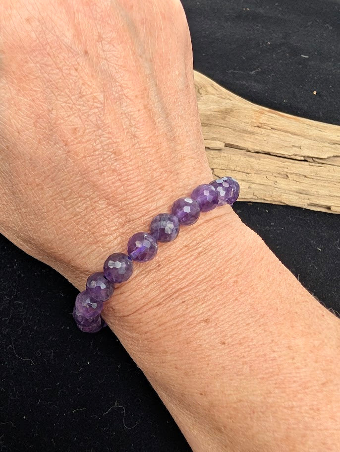 8mm faceted Amethyst beaded stretch bracelet worn on a wrist for size scale.