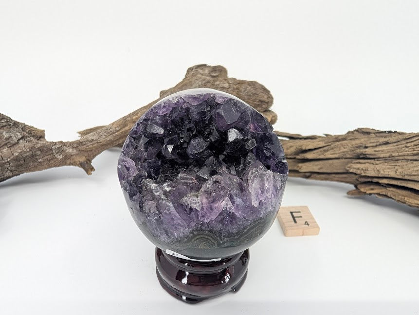 Exact-piece Uruguayan Amethyst Pac-Man sphere (Specimen F). Compact polished basalt sphere with bright violet vug.