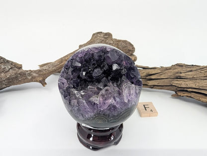 Exact-piece Uruguayan Amethyst Pac-Man sphere (Specimen F). Compact polished basalt sphere with bright violet vug.
