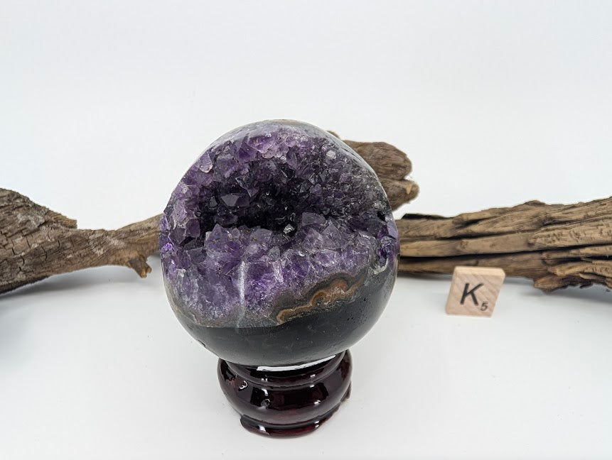 Exact-piece Uruguayan Amethyst Pac-Man sphere (Specimen K). Polished basalt matrix with unique lightning-bolt style opening.