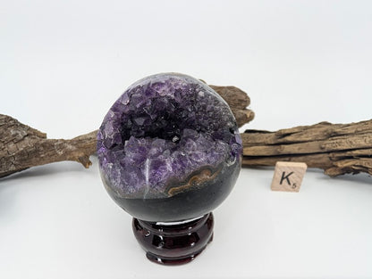 Exact-piece Uruguayan Amethyst Pac-Man sphere (Specimen K). Polished basalt matrix with unique lightning-bolt style opening.