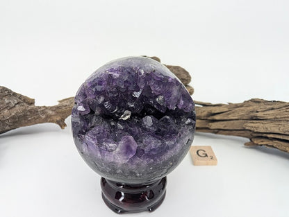 Exact-piece Uruguayan Amethyst Pac-Man sphere (Specimen G). Polished basalt matrix with triangular wedge-shaped crystal vug.