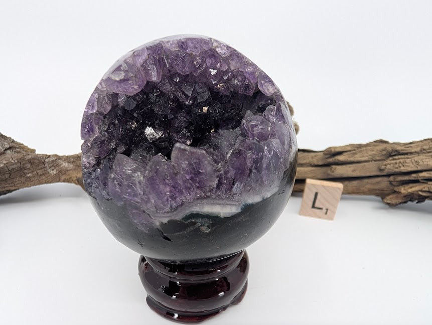 Exact-piece Uruguayan Amethyst Pac-Man sphere (Specimen L). Polished basalt matrix with deep glittering amethyst cavern.