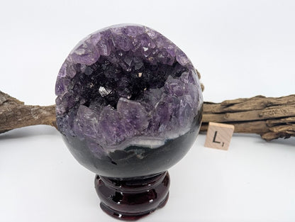 Exact-piece Uruguayan Amethyst Pac-Man sphere (Specimen L). Polished basalt matrix with deep glittering amethyst cavern.