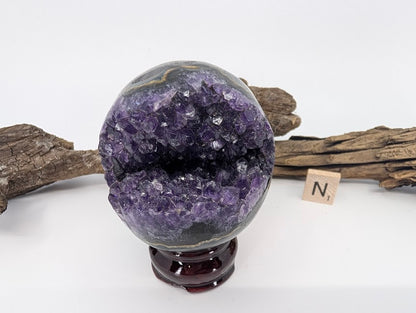 Exact-piece Uruguayan Amethyst Pac-Man sphere (Specimen N). Polished basalt matrix with distinct agate banding and crystal bite.