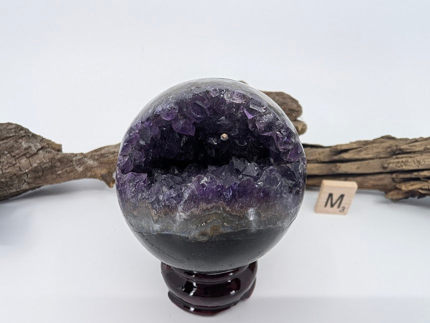 Exact-piece Uruguayan Amethyst Pac-Man sphere (Specimen M). Polished basalt matrix with enclosed cave-like violet vug.