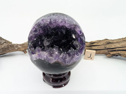 Exact-piece Uruguayan Amethyst Pac-Man sphere (Specimen J). Polished basalt matrix with high-saturation gemmy crystal points.