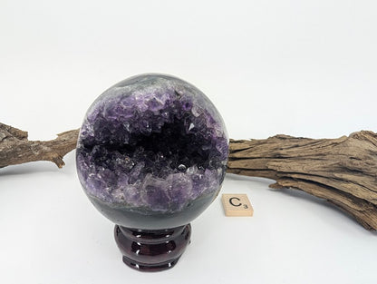 Exact-piece Uruguayan Amethyst Pac-Man sphere (Specimen C). Polished basalt matrix with deep throat-style cavern.