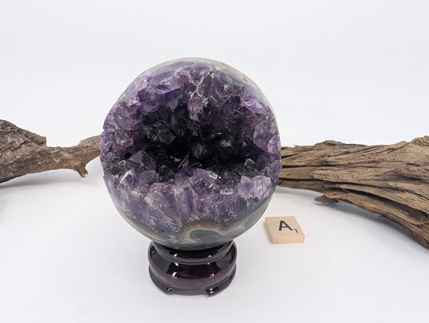 Exact-piece Uruguayan Amethyst Pac-Man sphere (Specimen A). Polished basalt matrix with deep purple crystal vug.