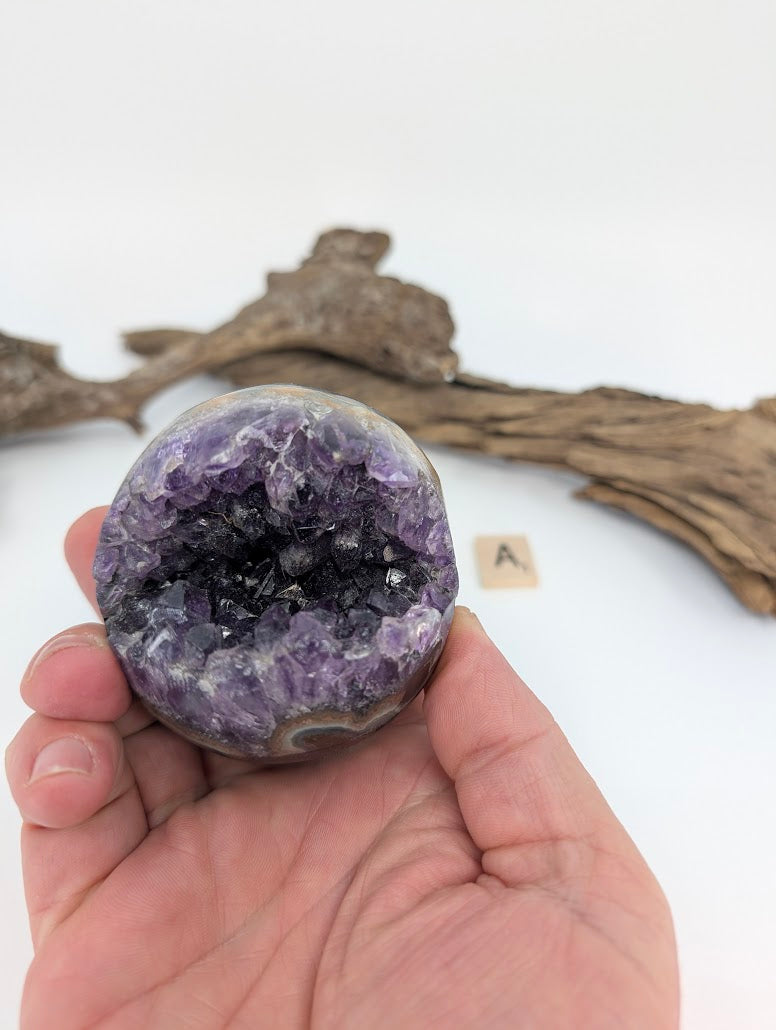 Hand-held view of Amethyst Pac-Man sphere showing size scale (Specimen A).