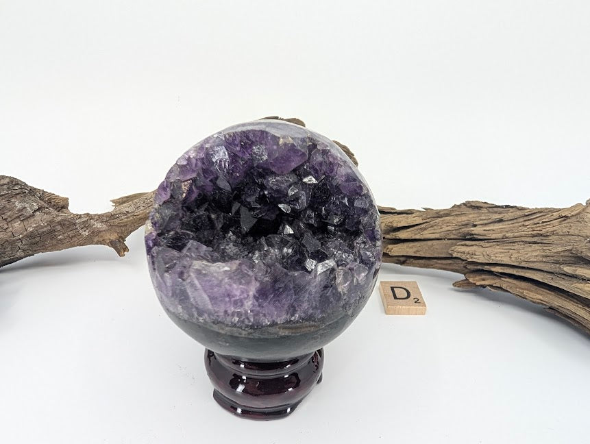 Exact-piece Uruguayan Amethyst Pac-Man sphere (Specimen D). Polished basalt matrix with jagged organic vug opening.