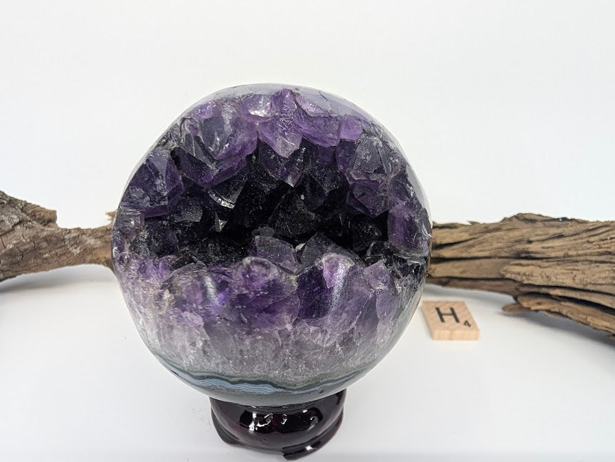 Exact-piece Uruguayan Amethyst Pac-Man sphere (Specimen H). Polished basalt matrix with white agate rim and deep purple cavern.