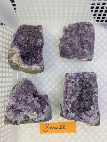 Natural Amethyst cut base vug in Small displaying a group of four deep purple quartz crystal clusters on a basalt matrix.