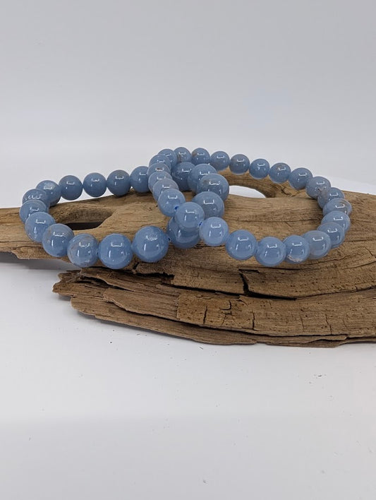 High quality Angelite bracelets displayed on natural wood showing rich periwinkle blue colour and polished round beads