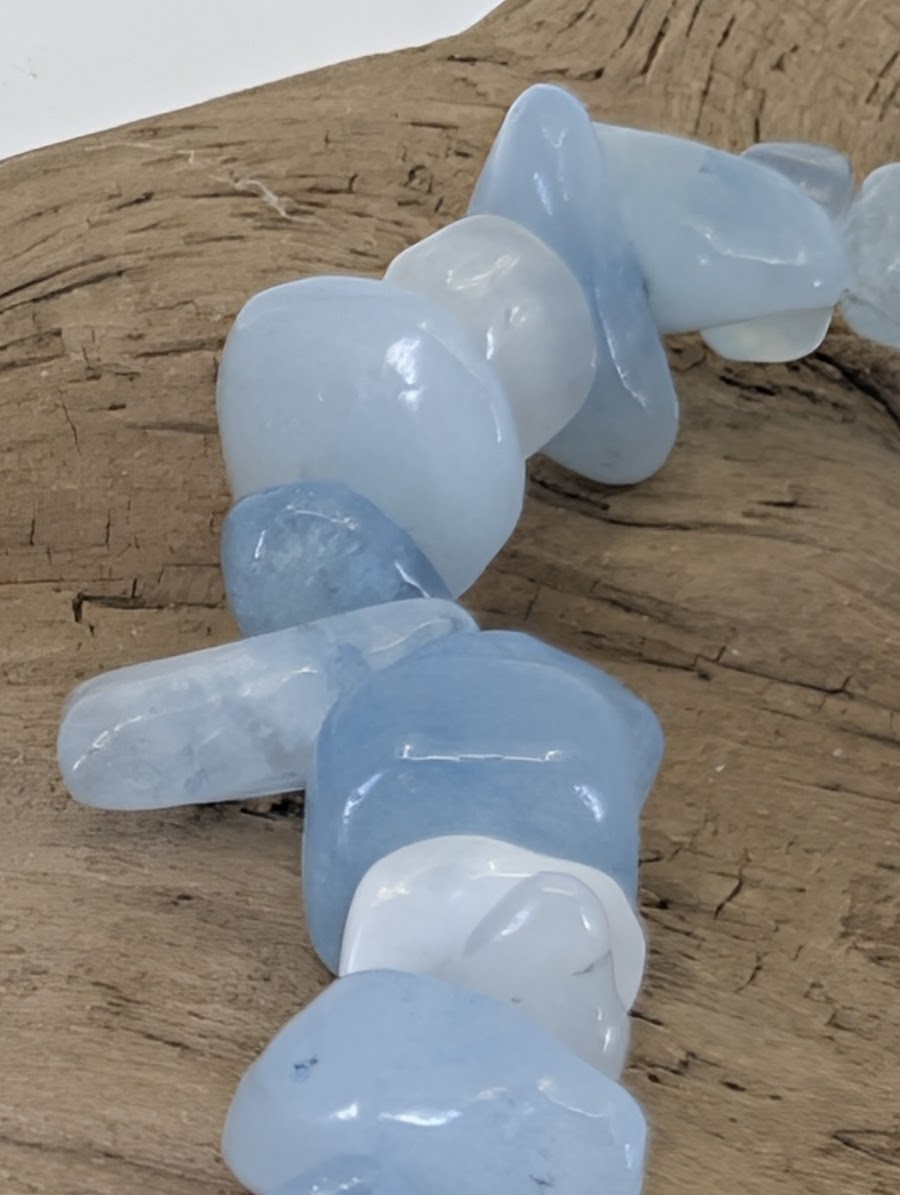 Macro view of tumbled Aquamarine fragments showing vitreous luster and authentic light-to-milky blue color zones.