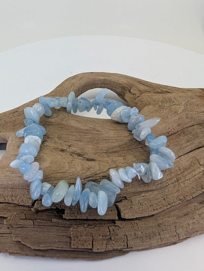 Natural Aquamarine chip bracelet from Brazil displayed on driftwood showing icy blue tumbled stones.