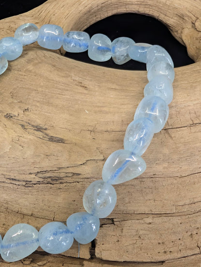 Macro shot of organic Aquamarine beads highlighting the natural "frozen water" internal structure.